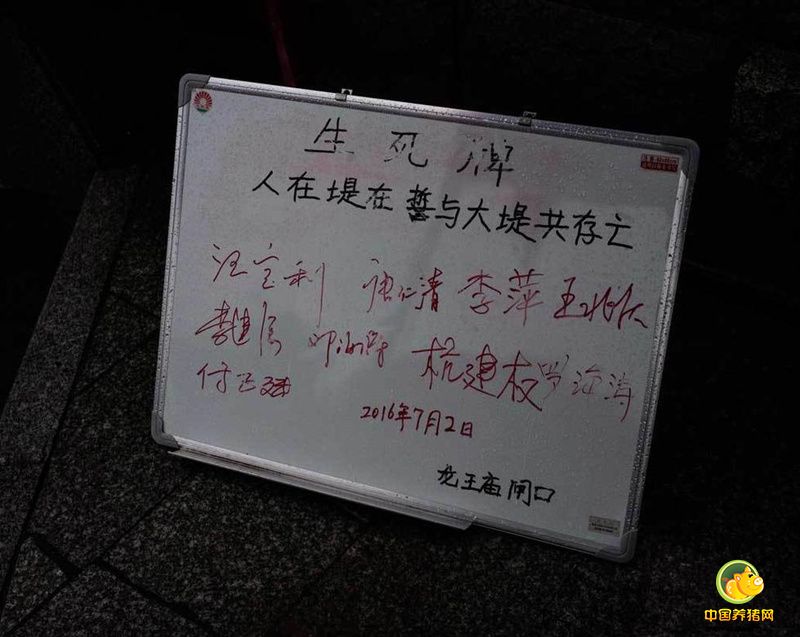 7月6日，武汉市遭遇特大暴雨袭击，长江水位超过28米，防汛形势极其严峻。位于两江交汇地的龙王庙码头一直以来都是武汉防汛的重中之重，记者在6日前往龙王庙码头附近探访时发现，沿江大道停满了各种渣土车，这些渣土车是用来运送防汛物资的。在马路边甚至堆放了各种防汛用的物品，比如黄沙、石子儿等等。图为武汉龙王庙码头立起防汛生死牌。