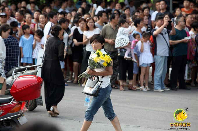 一位许昌市民手捧鲜花等待迎接两位维和烈士“回家”。