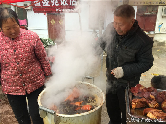 成师傅在翻动卤锅里的猪肉，他说这样能更好的入味，吃起来会更香更好吃，边上站的是成师傅家的老伴也是管钱的，她可是成师傅的得力帮手。