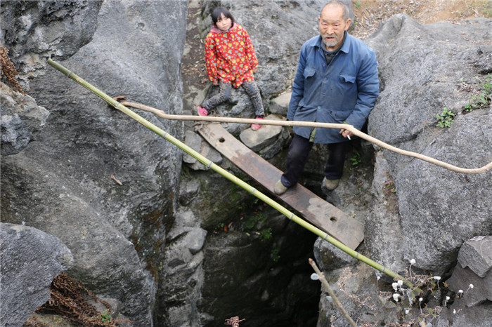 一家人每天用水，需要背上两到三趟。打水的天井，只有一块木板支撑，非常危险。小孙丽的爷爷每天就是这样站在木板上，用一根长棍汲水。 